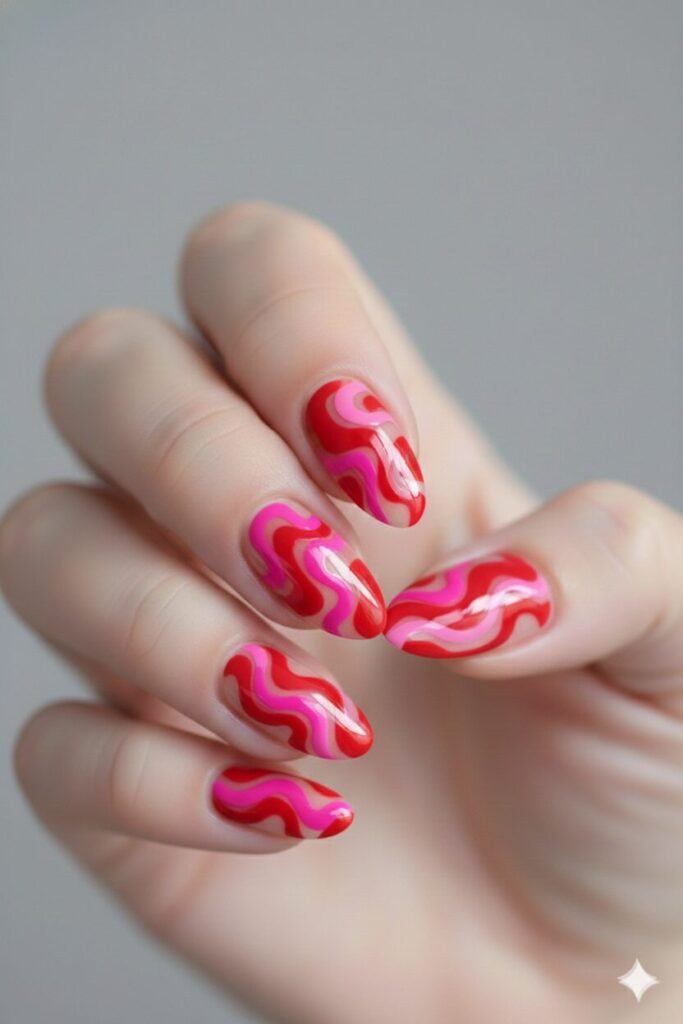 Trendy valentines nails featuring abstract hot pink and red swirls on a neutral base.