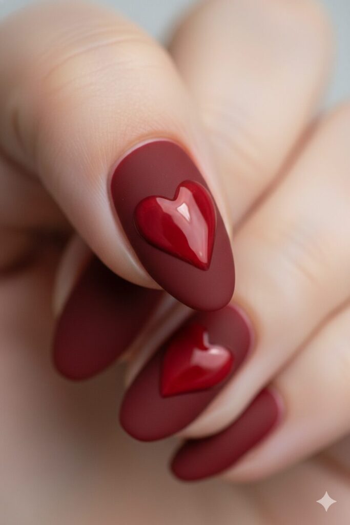 Chic valentines nails with a matte red base and a glossy heart design.