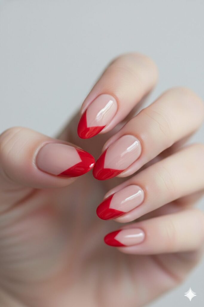 Modern valentines nails with red French tips shaped like hearts on a nude base.