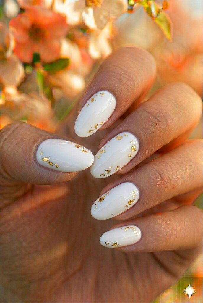 White spring nails with small gold foil accent pieces, luxurious elegant glamorous manicure for spring 2026