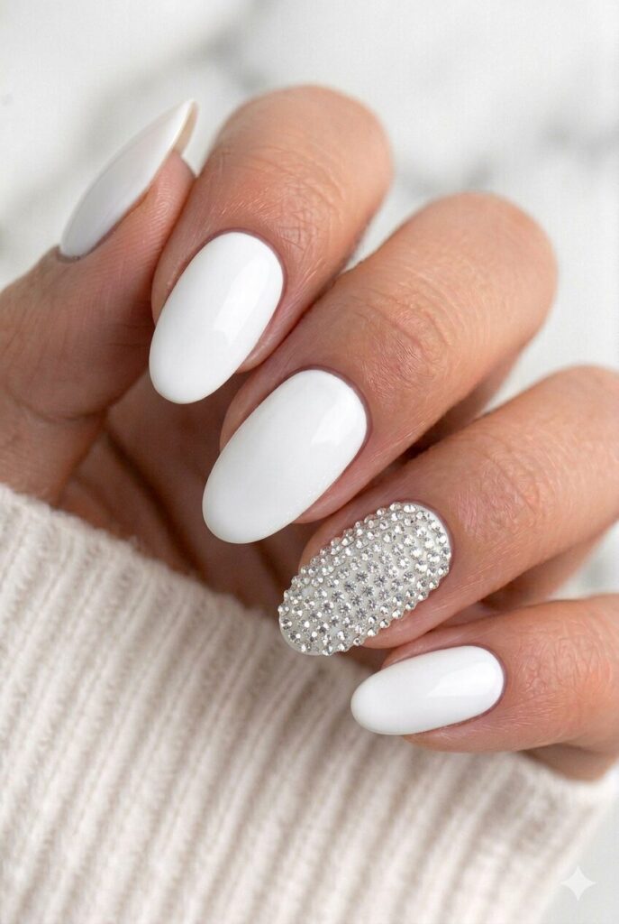 Graduation nails with a nude base and one full rhinestone accent nail for a glamorous look