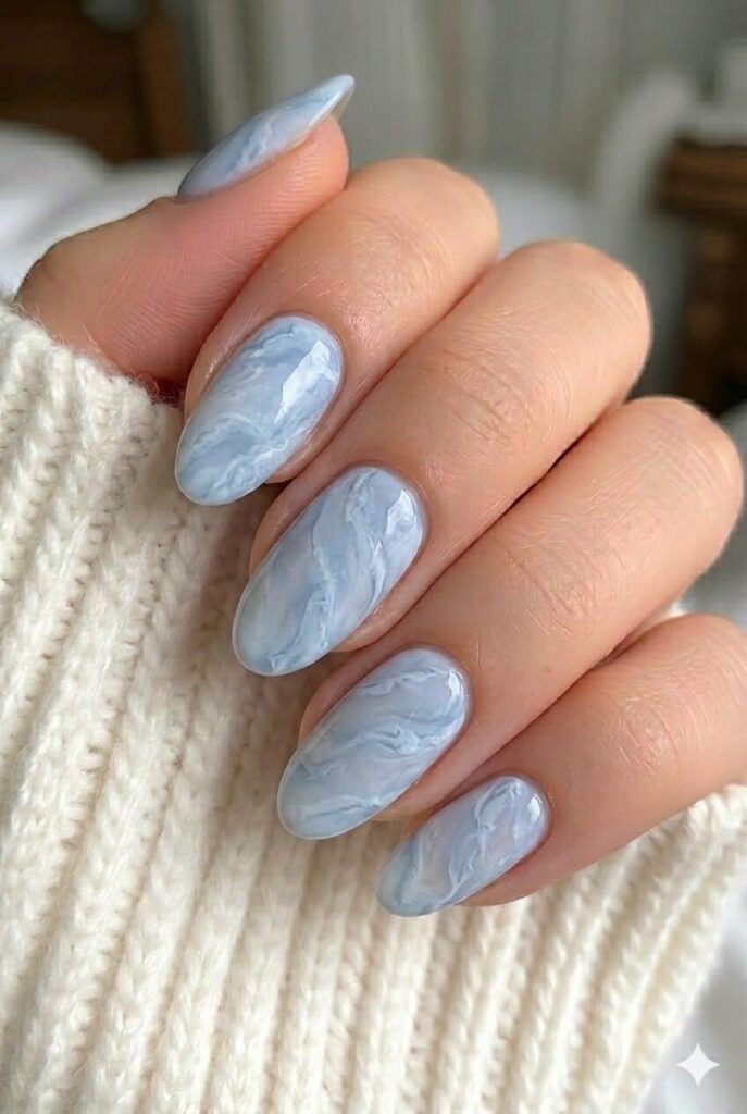 Soft blue marble prom nails with pale blue and white swirls for a luxury look