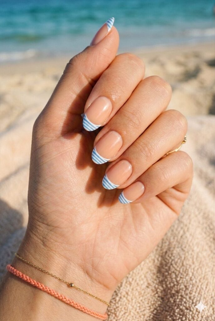 Short almond nails with nude base and blue white striped French tips