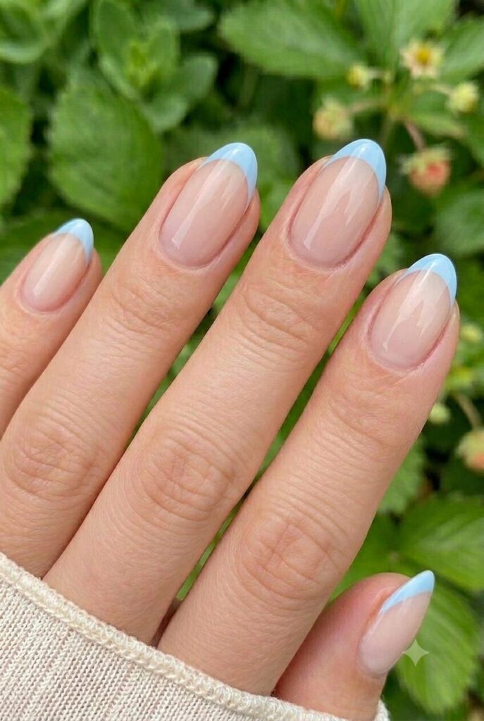 Short almond nails with nude base and sky blue French tips