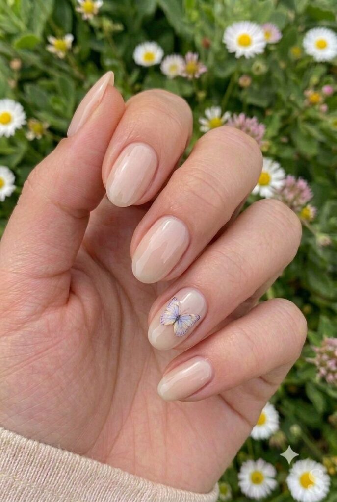 Short oval nails with nude base and tiny butterfly accent