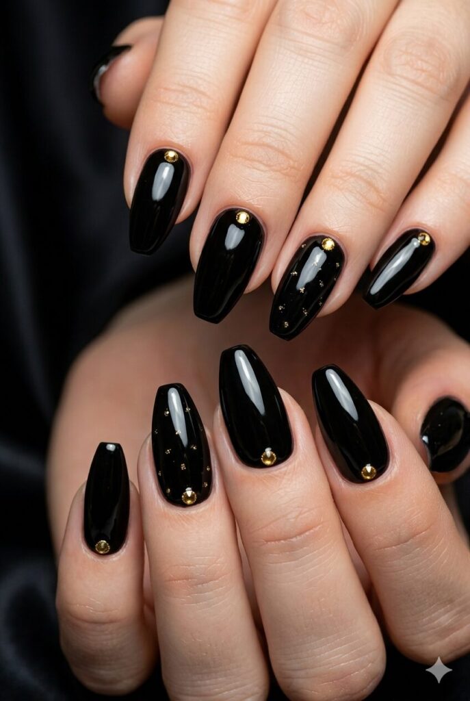Almond coffin nails with glossy black and tiny gold gem accents