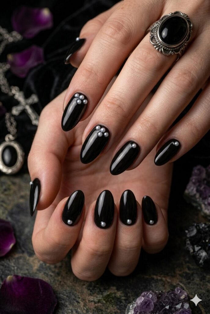Almond nails with glossy black polish and tiny white pearl accents