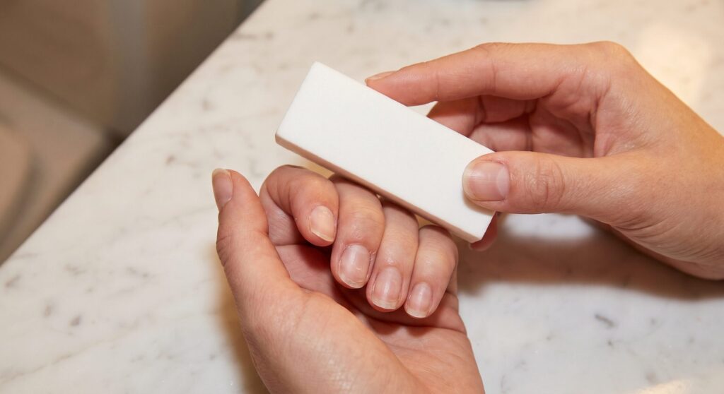 Buffing natural nails after gel x removal at home to smooth the nail surface