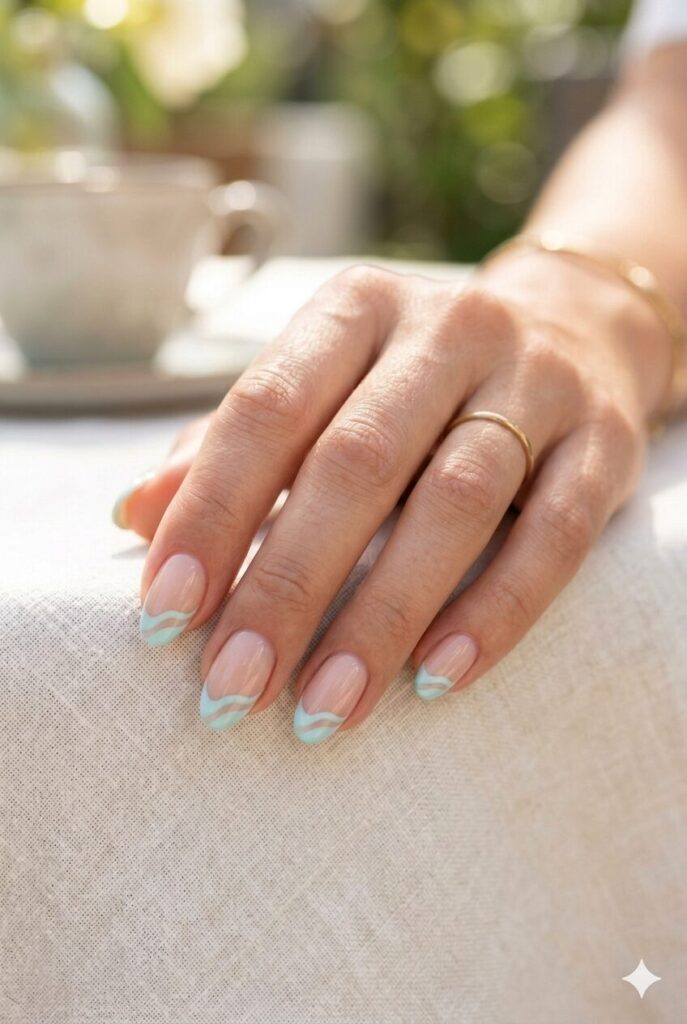 Short almond nails with nude base and pale aqua wave tips