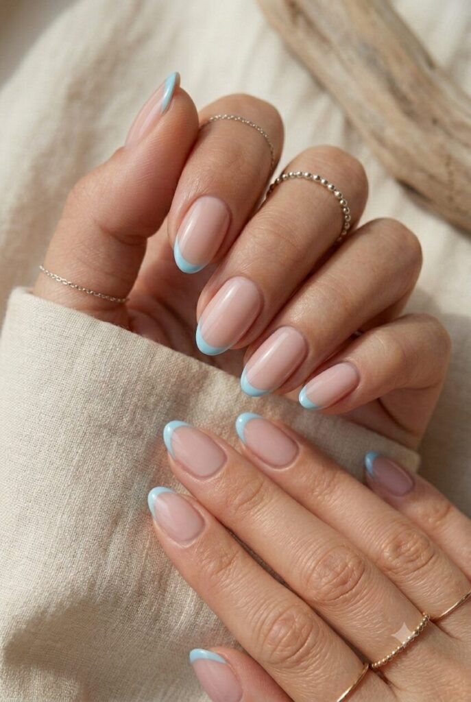 Short almond nails with nude base and sky blue French tips