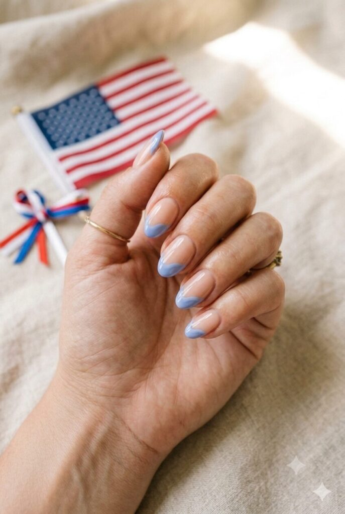 Short almond nails with nude base and soft blue wave French tips