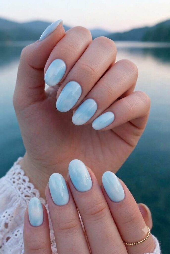 Short oval nails with glossy sky blue and white blended polish