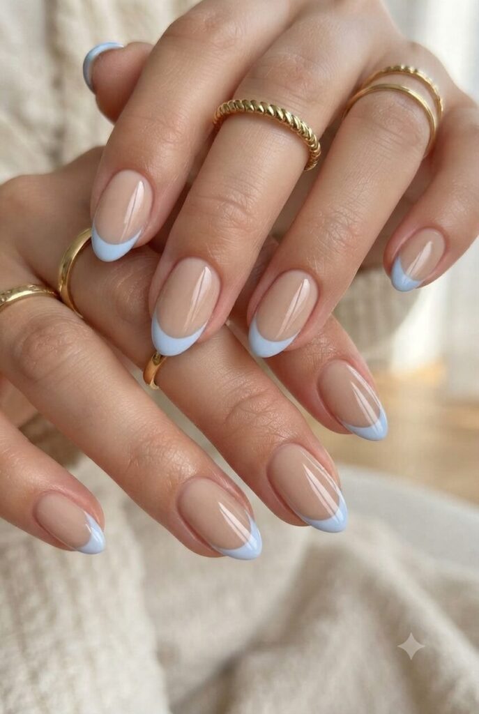 Short almond nails with nude base and soft powder blue French tips