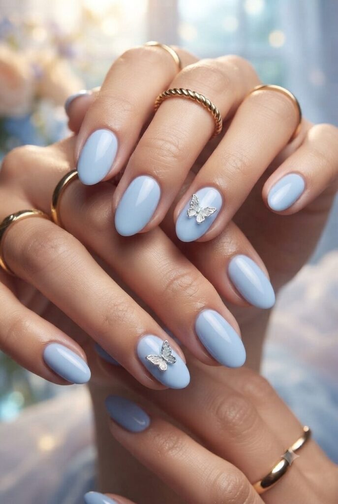Short almond nails with blue base and tiny silver butterfly accents