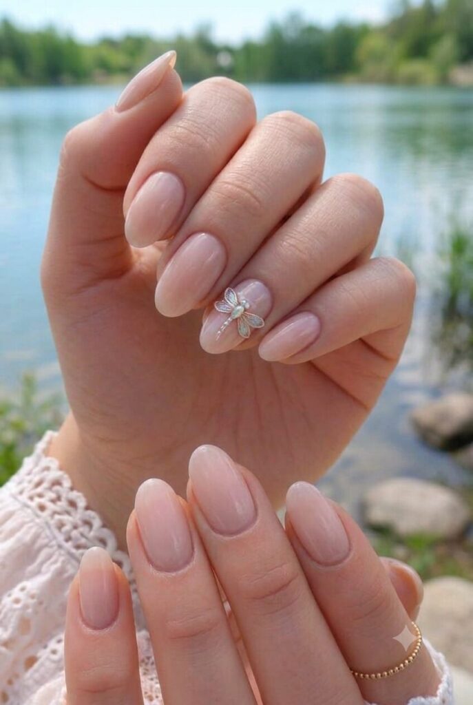 Short almond nails with nude base and tiny dragonfly accent