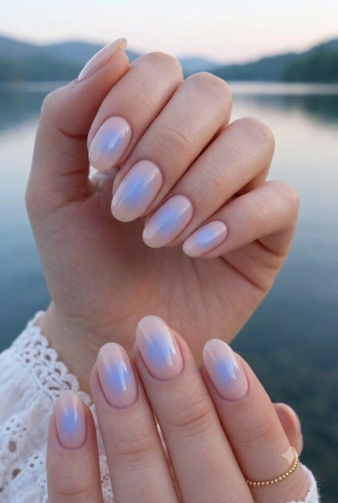 Short almond nails with nude base and soft blue aura glow center
