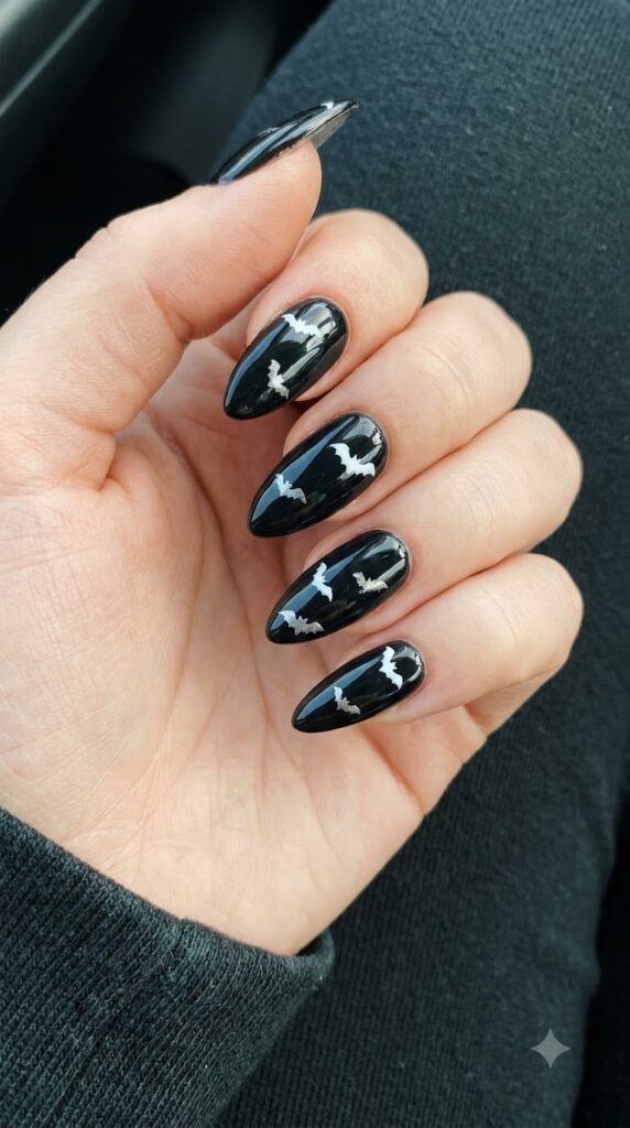 Pointed almond nails in glossy black with tiny white flying bats