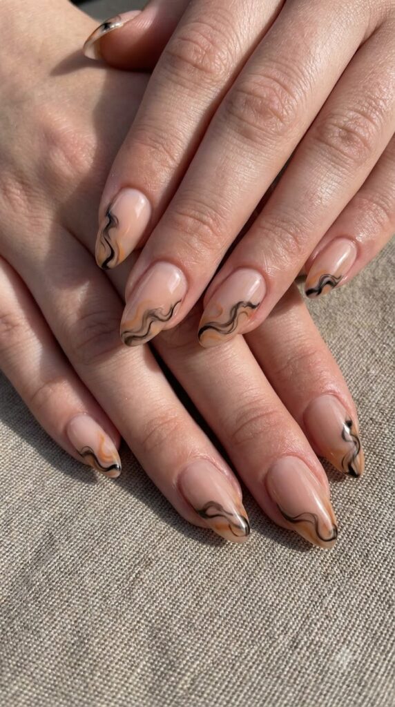 Almond nude nails with wispy black and orange smoke cloud trails
