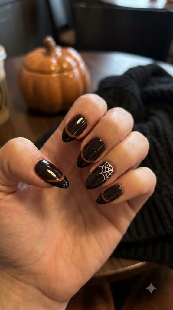Almond nails with black and orange French tips and spider web detail
