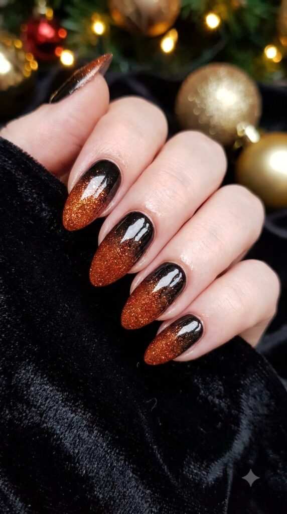 Oval nails with black polish fading into orange glitter ombre
