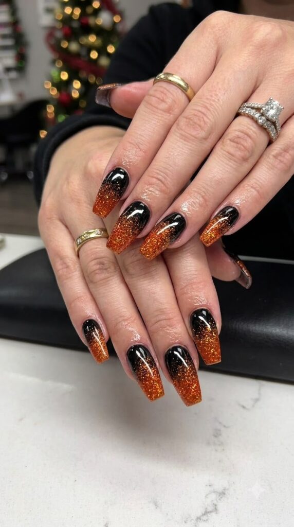Coffin acrylic nails with black polish and orange glitter ombre