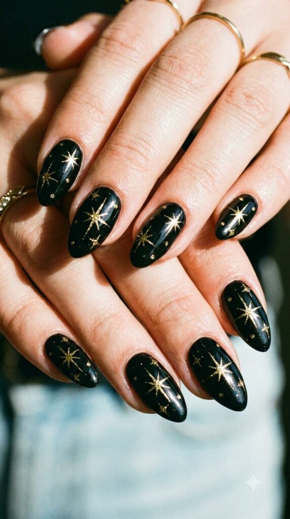 Almond black nails decorated with fine golden starburst decals