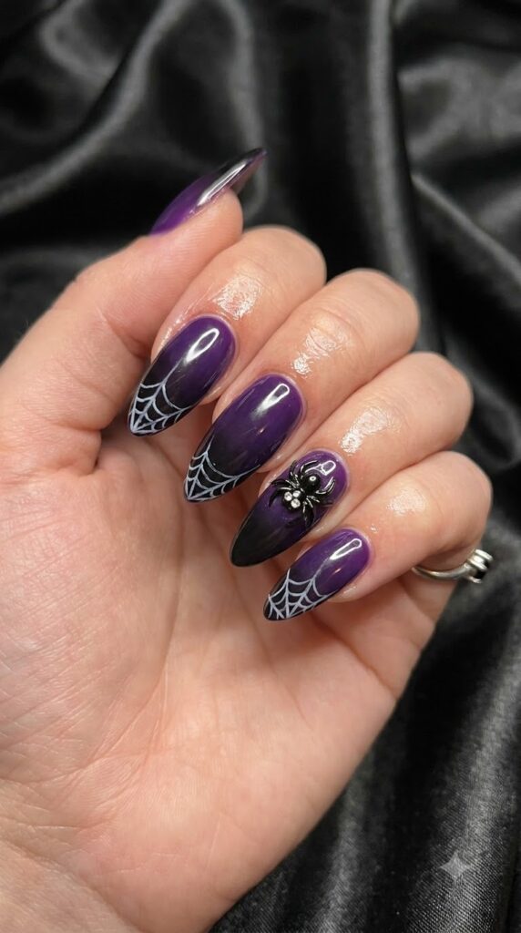 Almond nails with purple black polish and thin white spider webs