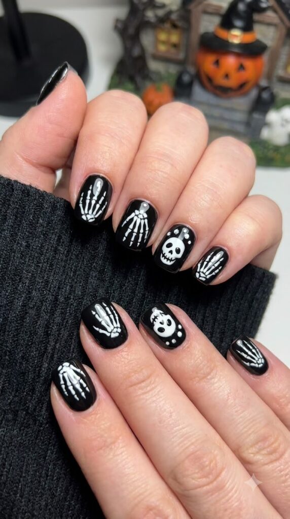 Short black nails painted with white skeleton bones and skulls