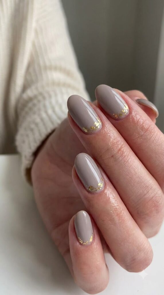 Oval nails with muted grey polish and gold foil accents