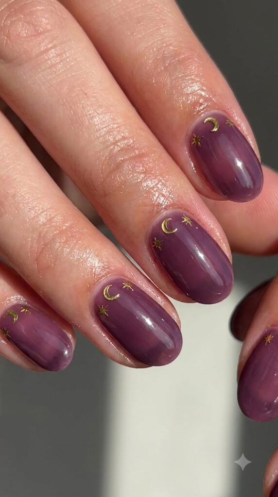 Short oval deep plum nails with metallic gold crescent moon charms