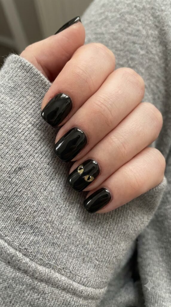 Short square black nails with golden cat eyes peeking from cuticle