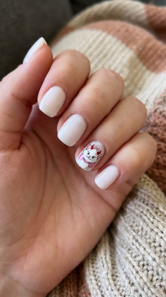Short round white nails with Marie cat wearing red devil horns