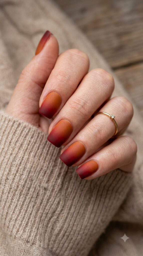 Short square burnt orange nails fading into crimson red with matte finish