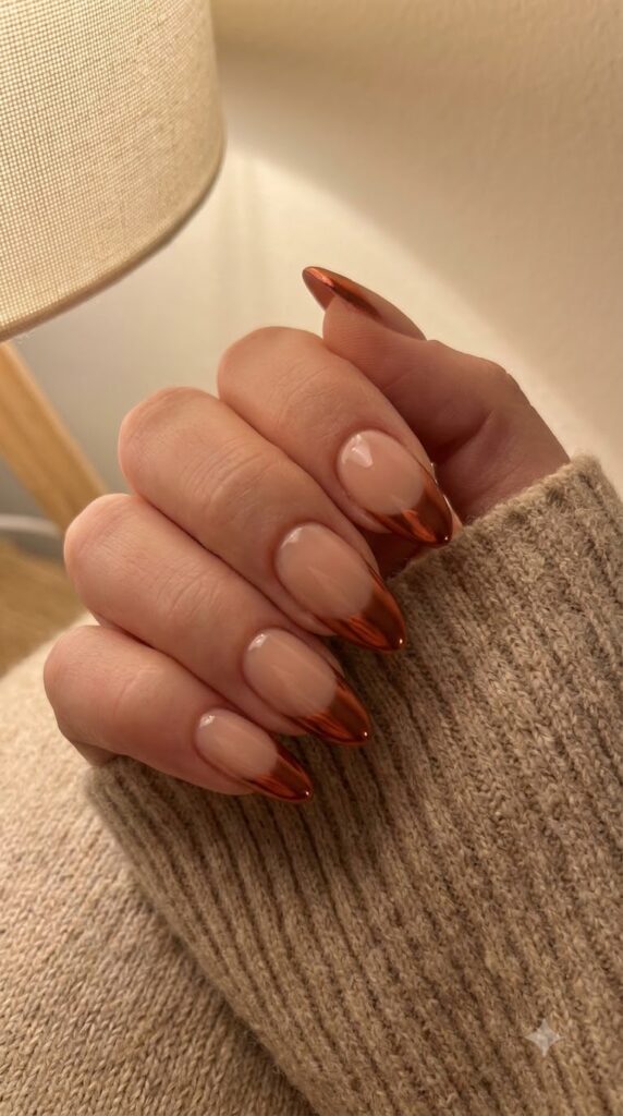 Almond nude nails fading smoothly into metallic cinnamon red chrome tips