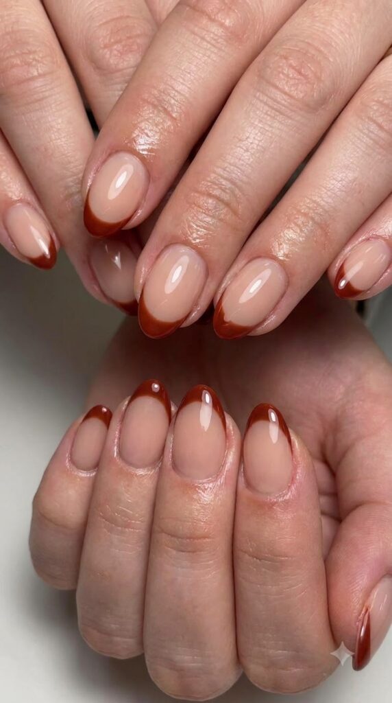 Short almond nude gel nails with crisp cinnamon red French tips