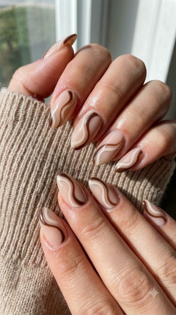 Almond milky nude gel nails decorated with espresso brown and cream swirls