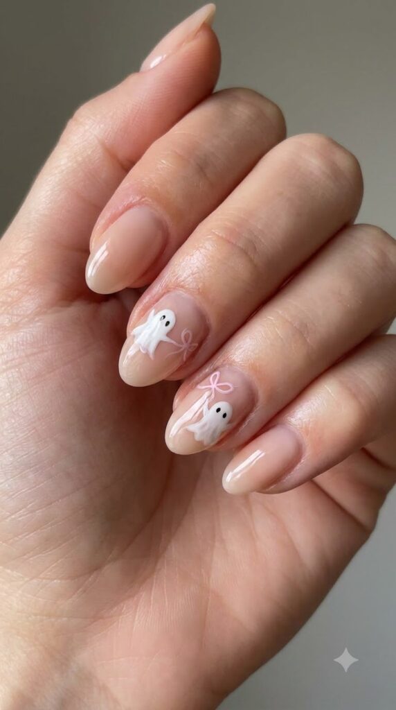 Short almond nude nails with white floating ghosts tied with a pink bow