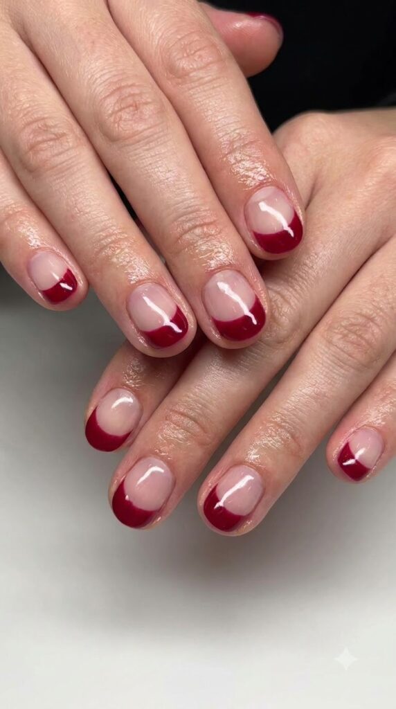 Short round clear gel nails with painted deep cherry red cuticle half-moons