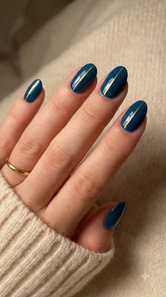 Oval dark teal-blue nails decorated with a single vertical gold center stripe