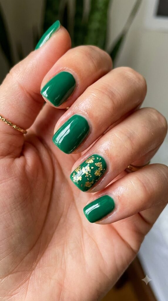 Short squoval rich emerald green nails with scattered gold leaf foil flecks