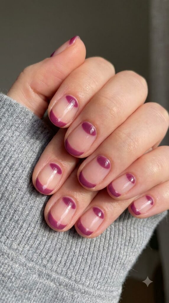 Short round clear nails with painted deep plum pink cuticle half-moons