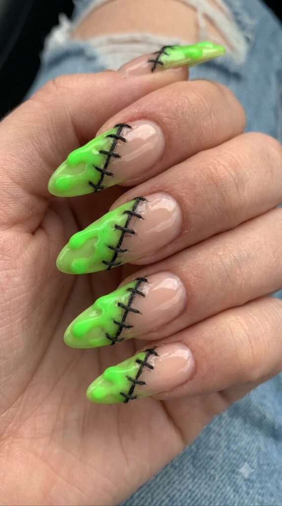 Almond nude nails split diagonally with neon green slime drips and stitches