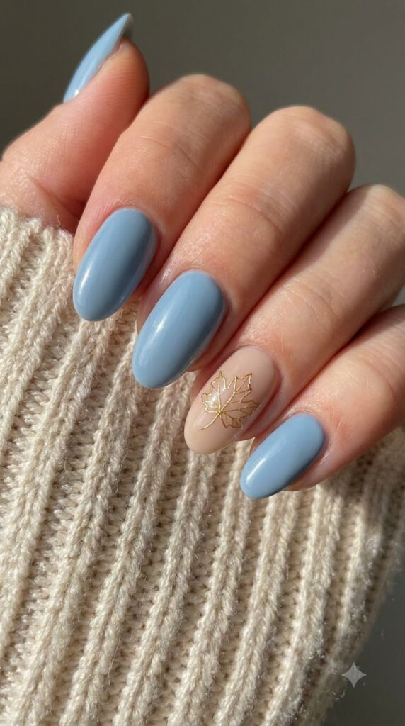 Oval dusty sky blue nails with nude accent nail featuring gold maple leaf art