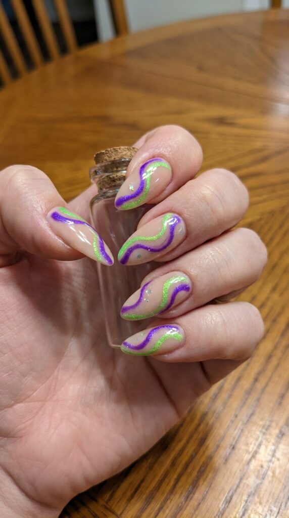 Long almond nude nails with swirling electric purple and neon green potion lines