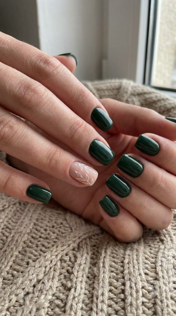 Short square forest green nails with a nude accent nail featuring leaf art