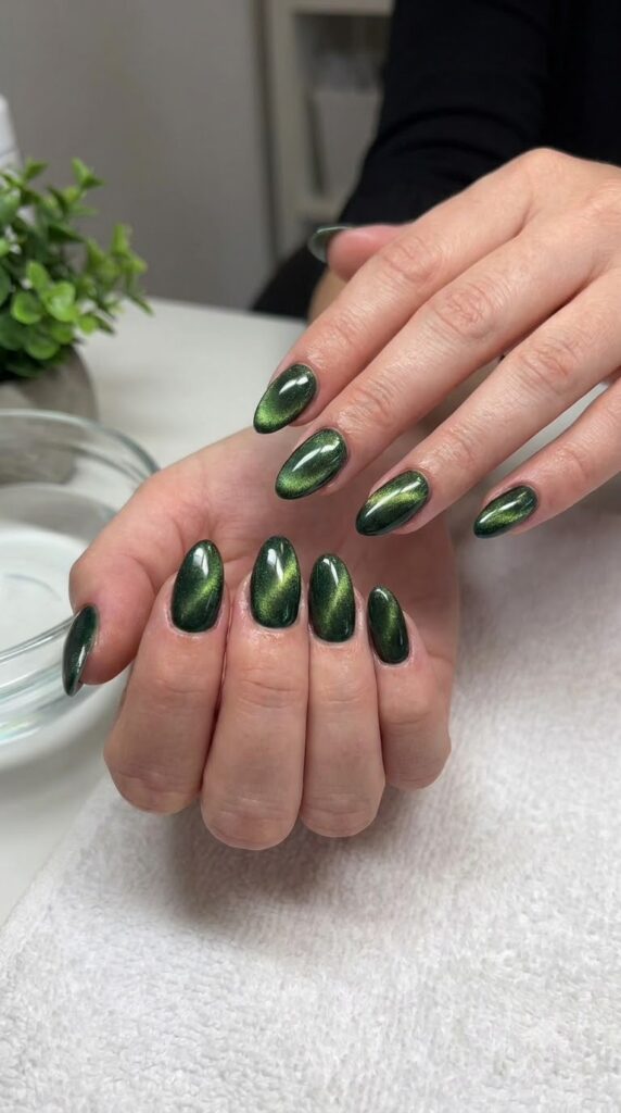 Medium almond nails with rich forest green magnetic cat-eye velvet polish