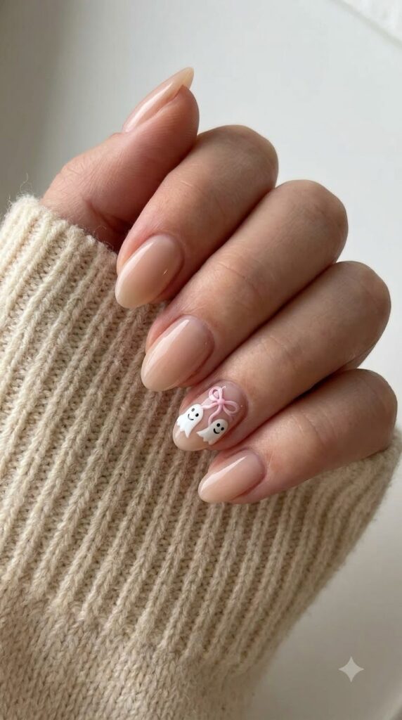 Short almond nude nails with white floating ghosts tied with a pink bow