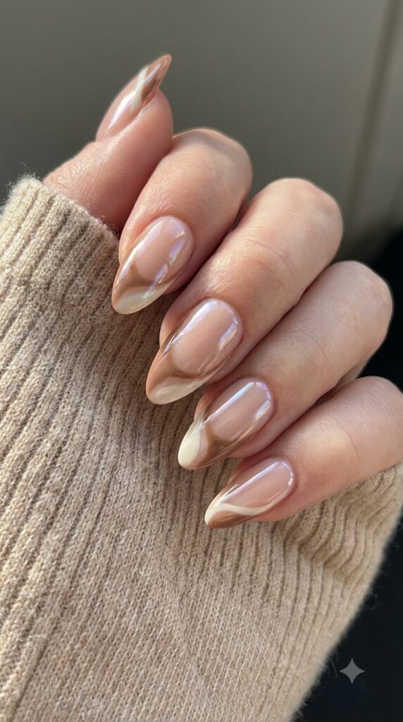 Almond nails with nude base, latte brown swirls, and glazed chrome finish
