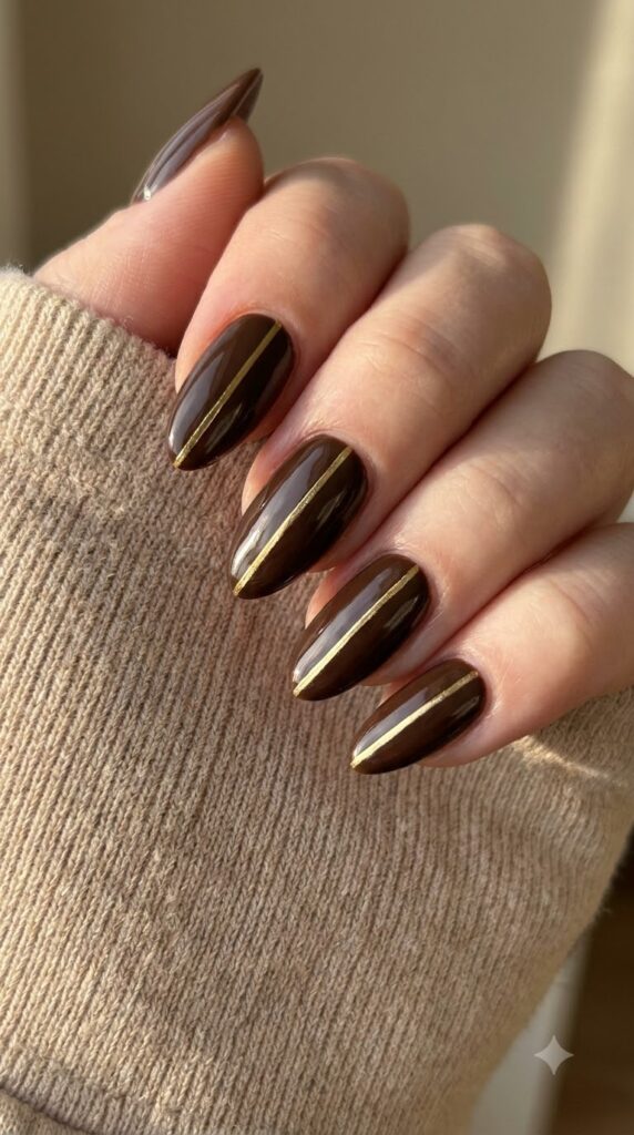 Almond deep brown gel nails decorated with a vertical gold chrome stripe