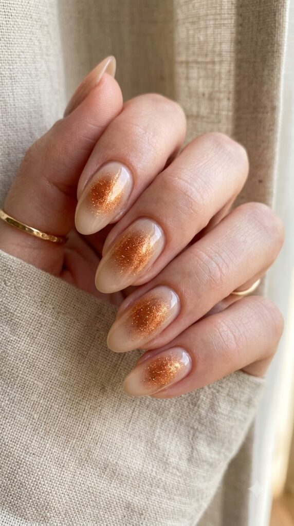 Medium almond sheer beige nails with a glowing copper shimmer aura center